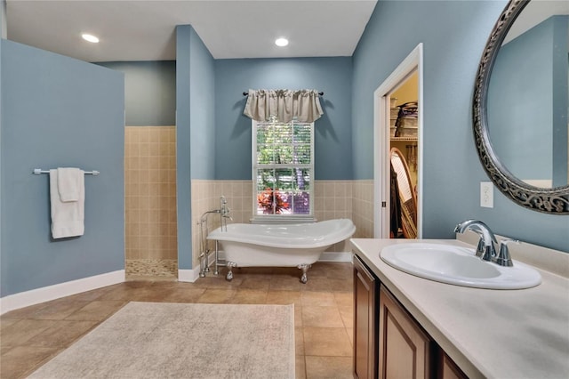 16420 Iola Woods Trl, Dade City, FL 33523 - full bathroom featuring a freestanding tub, vanity, a spacious closet, tile patterned flooring, and tile walls