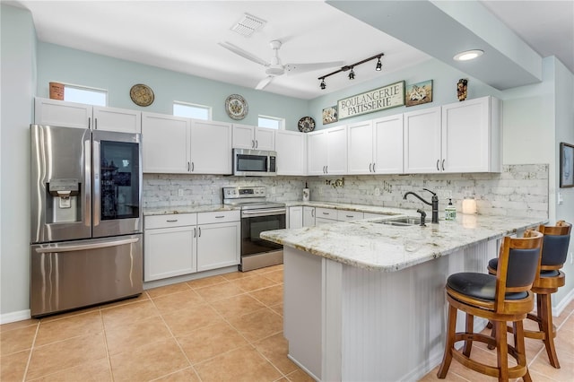 8116 Sanguinelli Rd, Land O Lakes, FL 34637 - kitchen with visible vents, a sink, a peninsula, appliances with stainless steel finishes, and white cabinetry