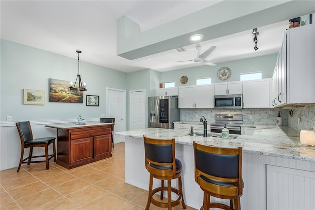 8116 Sanguinelli Rd, Land O Lakes, FL 34637 - kitchen featuring a peninsula, light tile patterned flooring, tasteful backsplash, and stainless steel appliances
