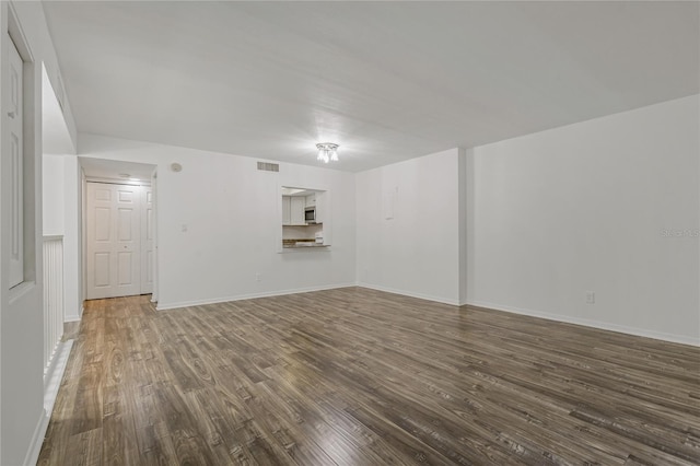 105 4th Ave NE Unit 220, Saint Petersburg, FL 33701 - unfurnished living room featuring visible vents, baseboards, and dark wood finished floors