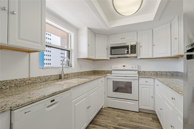 105 4th Ave NE Unit 220, Saint Petersburg, FL 33701 - kitchen with a sink, white appliances, a tray ceiling, white cabinetry, and wood finished floors