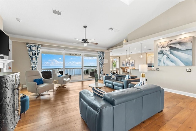 living area featuring light wood finished floors, a water view, visible vents, lofted ceiling, and ceiling fan