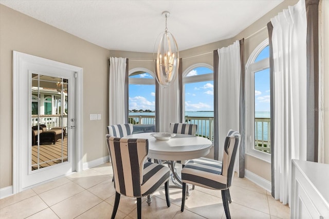 dining area with an inviting chandelier, light tile patterned floors, a water view, and baseboards