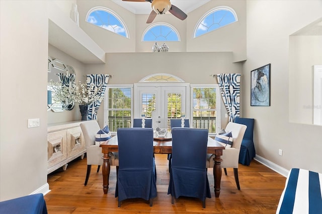 dining space featuring wood finished floors, a healthy amount of sunlight, baseboards, and french doors