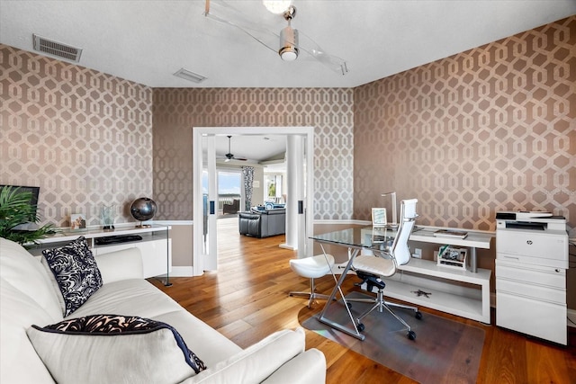 home office with wallpapered walls, wood finished floors, and visible vents