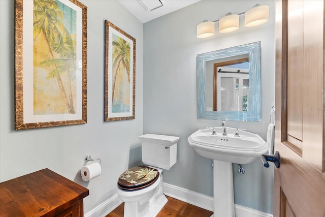 bathroom with wood finished floors, baseboards, and toilet