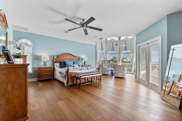 bedroom featuring hardwood / wood-style flooring, visible vents, access to outside, and multiple windows
