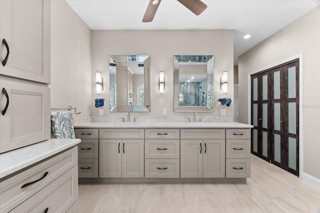 bathroom featuring ceiling fan, walk in shower, double vanity, and a sink