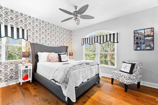 bedroom featuring multiple windows, wallpapered walls, and baseboards