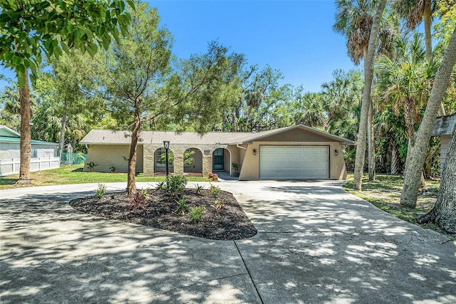 ranch-style home with stucco siding, fence, an attached garage, and curved driveway