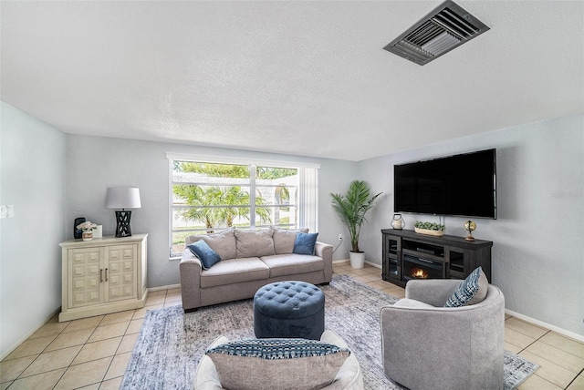 tiled living area with a textured ceiling, baseboards, and visible vents