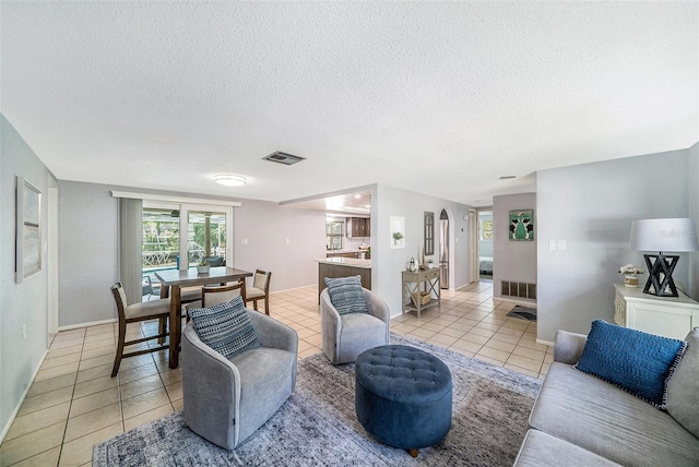 living room featuring light tile patterned floors, visible vents, and a textured ceiling