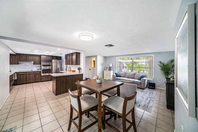 dining space featuring visible vents, light tile patterned flooring, and a textured ceiling