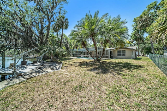 view of yard with an outdoor pool, a fenced backyard, a dock, and a lanai