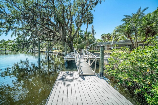 view of dock with glass enclosure and a water view