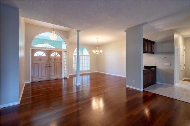 9159 Highland Ridge Way, Tampa, FL 33647 - foyer entrance featuring ornate columns, a notable chandelier, light wood-type flooring, and baseboards