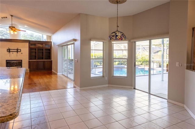9159 Highland Ridge Way, Tampa, FL 33647 - unfurnished dining area with high vaulted ceiling, a ceiling fan, tile patterned flooring, a glass covered fireplace, and baseboards