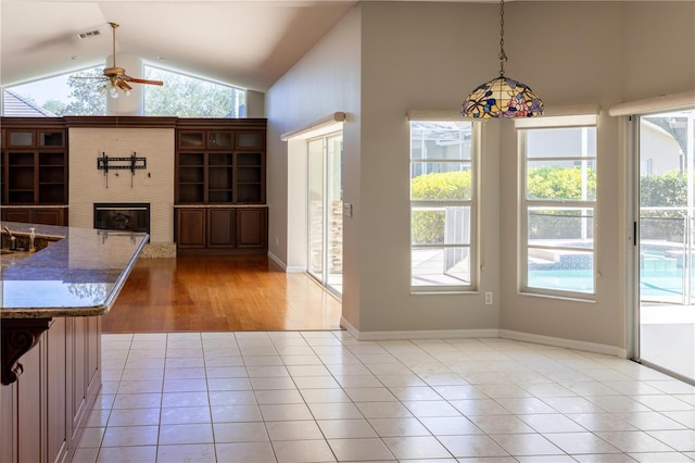 9159 Highland Ridge Way, Tampa, FL 33647 - unfurnished dining area with visible vents, light tile patterned floors, ceiling fan, high vaulted ceiling, and a glass covered fireplace