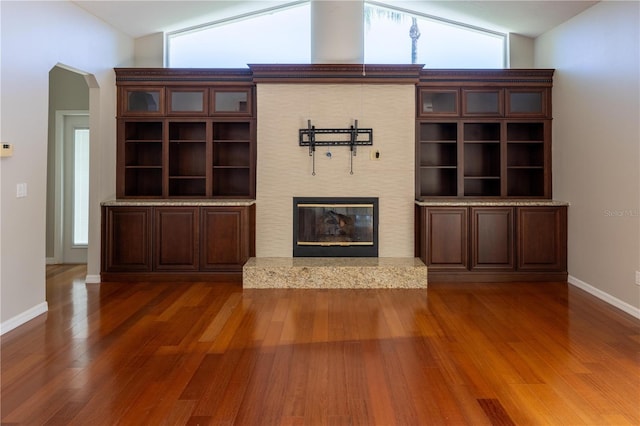 9159 Highland Ridge Way, Tampa, FL 33647 - unfurnished living room featuring baseboards, arched walkways, a glass covered fireplace, and wood finished floors