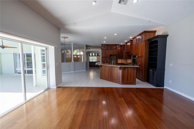 9159 Highland Ridge Way, Tampa, FL 33647 - kitchen with stainless steel oven, light wood finished floors, a kitchen breakfast bar, and vaulted ceiling
