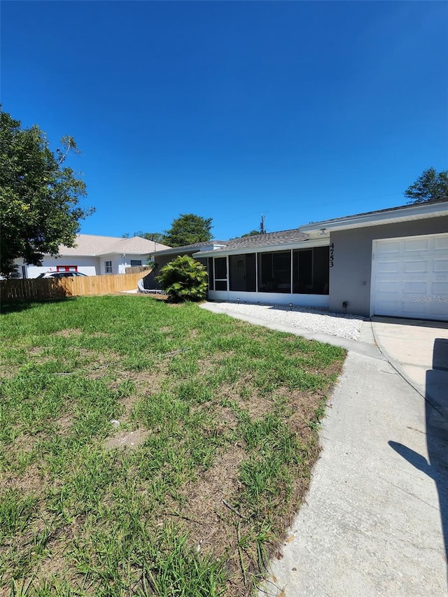 view of yard featuring an attached garage, fence, and a sunroom