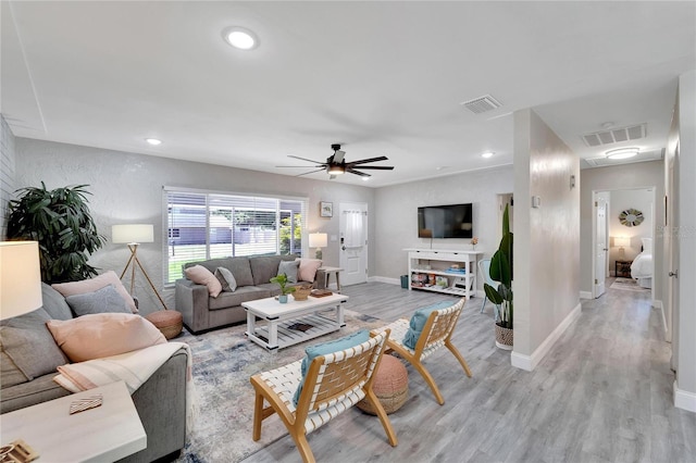 living room with ceiling fan, baseboards, visible vents, and light wood-style flooring