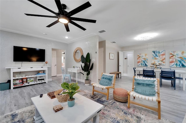 living room with wood finished floors, visible vents, a ceiling fan, and baseboards