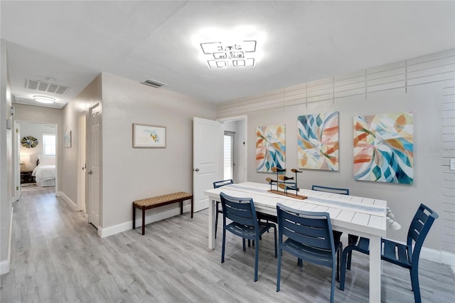 dining space with light wood-type flooring, visible vents, and plenty of natural light