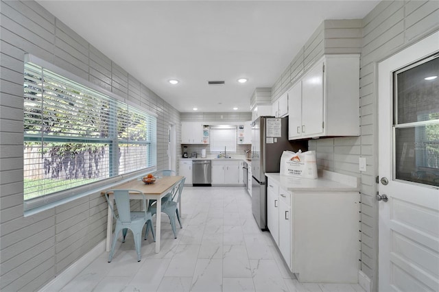 kitchen featuring stainless steel appliances, a sink, visible vents, marble finish floor, and light countertops