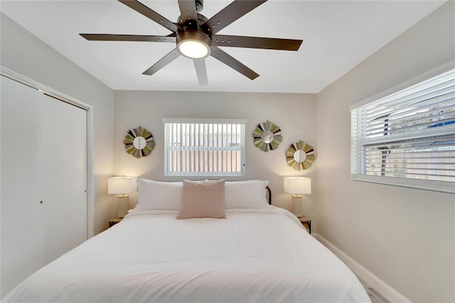 bedroom featuring baseboards, a ceiling fan, multiple windows, and a closet