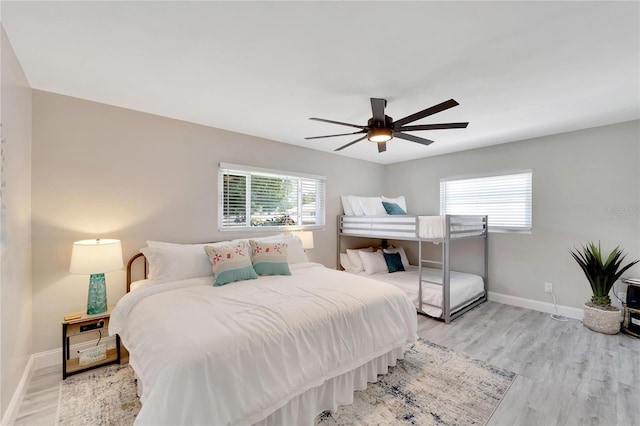 bedroom with light wood finished floors, a ceiling fan, and baseboards