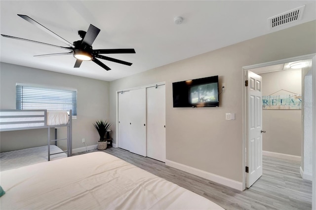 bedroom with a closet, light wood-type flooring, ceiling fan, baseboards, and visible vents