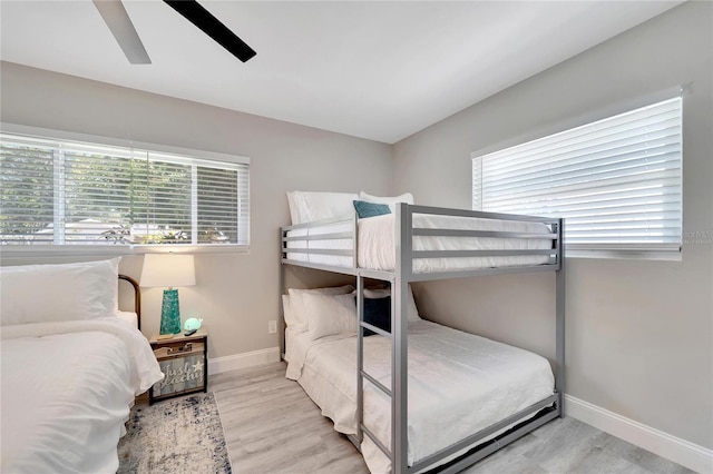 bedroom with baseboards, wood finished floors, and multiple windows