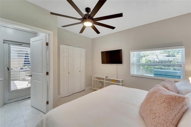 bedroom featuring marble finish floor, a ceiling fan, and a closet