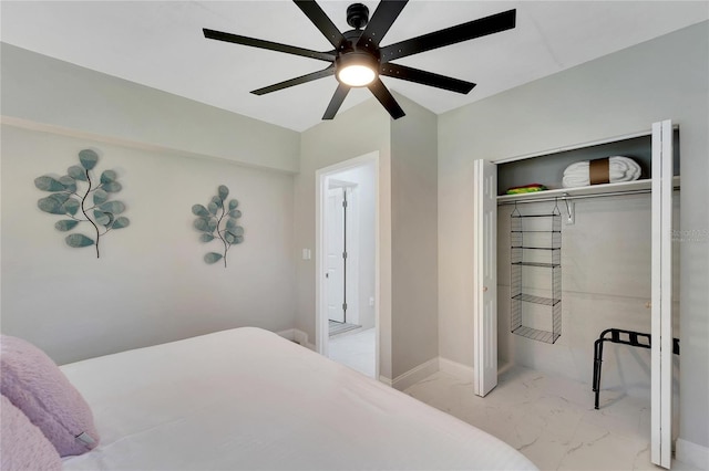 bedroom with baseboards, a ceiling fan, marble finish floor, and a closet