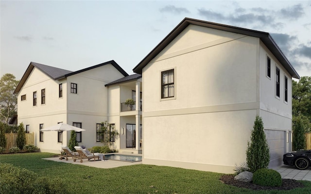 rear view of property featuring a lawn, a patio area, a balcony, and stucco siding