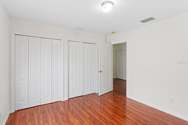 20123 Bay Cedar Ave, Tampa, FL 33647 - unfurnished bedroom featuring two closets, baseboards, wood finished floors, and visible vents