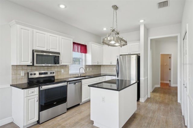 6518 Paw Pl, Land O Lakes, FL 34639 - kitchen with stainless steel appliances, backsplash, a sink, white cabinetry, and visible vents