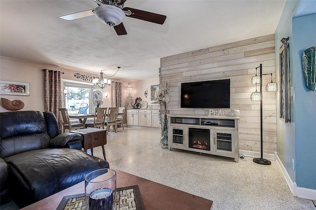 5931 33rd Ave N, Saint Petersburg, FL 33710 - living area with baseboards, speckled floor, ceiling fan with notable chandelier, wood walls, and a lit fireplace