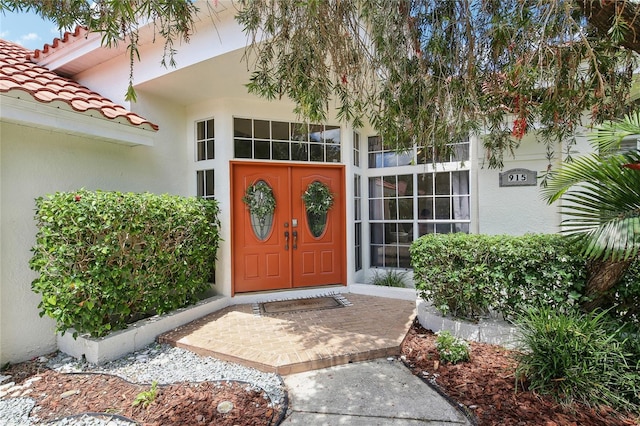 view of exterior entry with a tile roof and stucco siding
