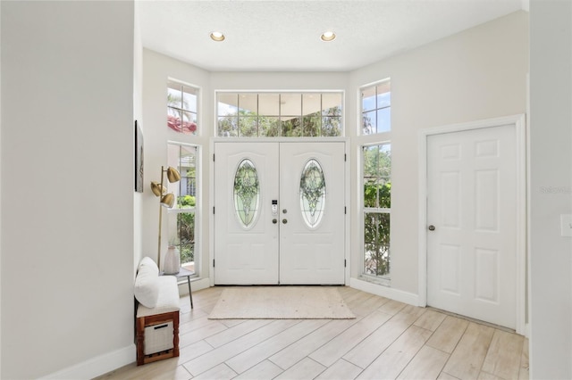 foyer with baseboards, light wood-style flooring, a high ceiling, and recessed lighting