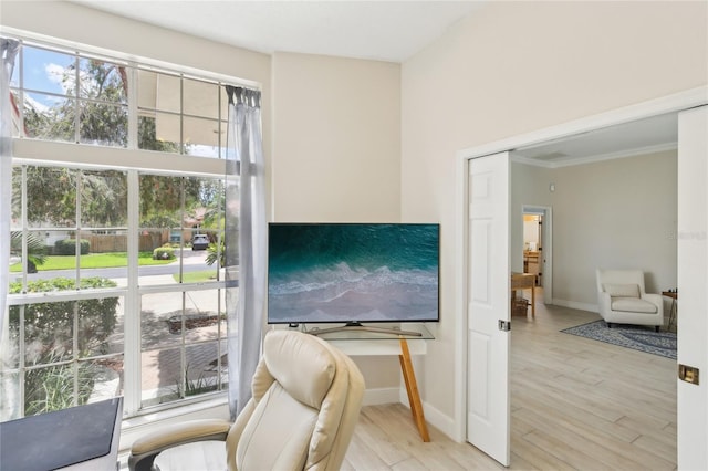 living area featuring light wood-style flooring, crown molding, and baseboards