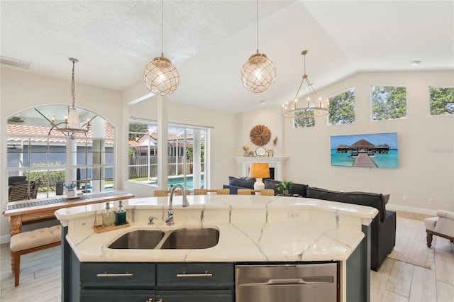 kitchen featuring an island with sink, open floor plan, a sink, and an inviting chandelier