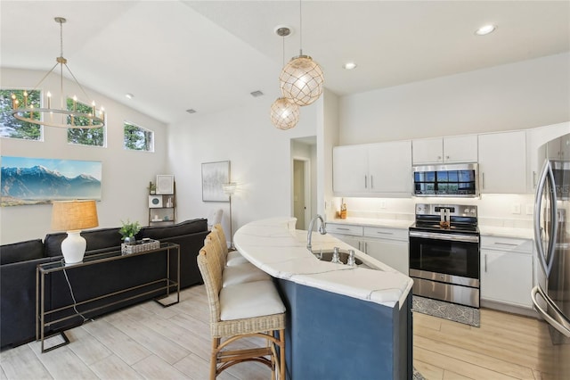 kitchen with light wood finished floors, an inviting chandelier, a sink, appliances with stainless steel finishes, and open floor plan