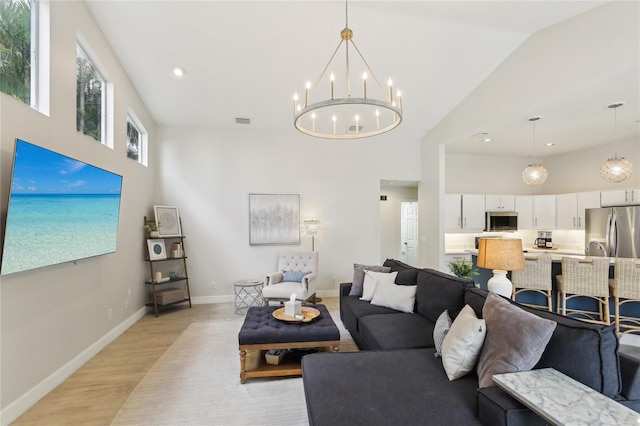 living room with baseboards, light wood finished floors, high vaulted ceiling, and an inviting chandelier