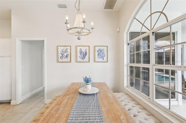 dining space with an inviting chandelier, wood finished floors, visible vents, and baseboards