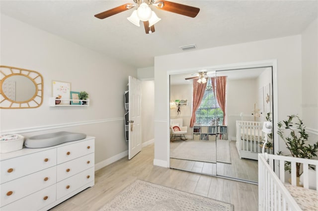 bedroom with a closet, light wood-style floors, visible vents, and a ceiling fan