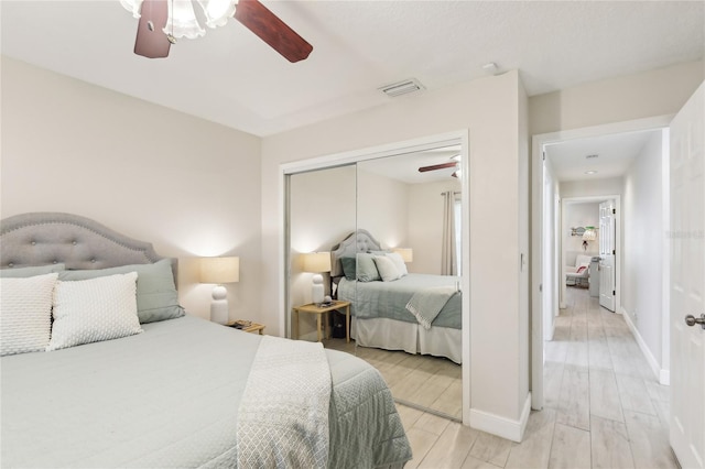 bedroom with baseboards, visible vents, light wood-style floors, a closet, and ceiling fan