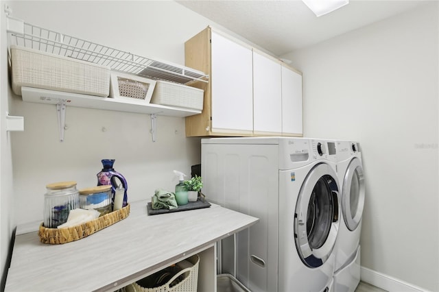 washroom with washing machine and dryer, baseboards, and cabinet space