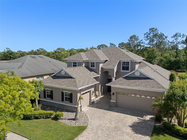 27318 Sora Blvd, Wesley Chapel, FL 33544 - view of front of home with stone siding, a garage, stucco siding, decorative driveway, and roof with shingles
